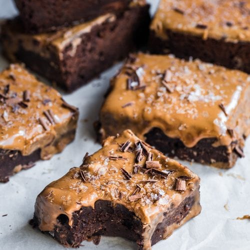 5 brownies on parchment paper, one with a bite taken from it.