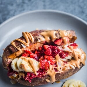 baked sweet potato stuffed with peanut butter, raspberry chia jam, bananas, and strawberries
