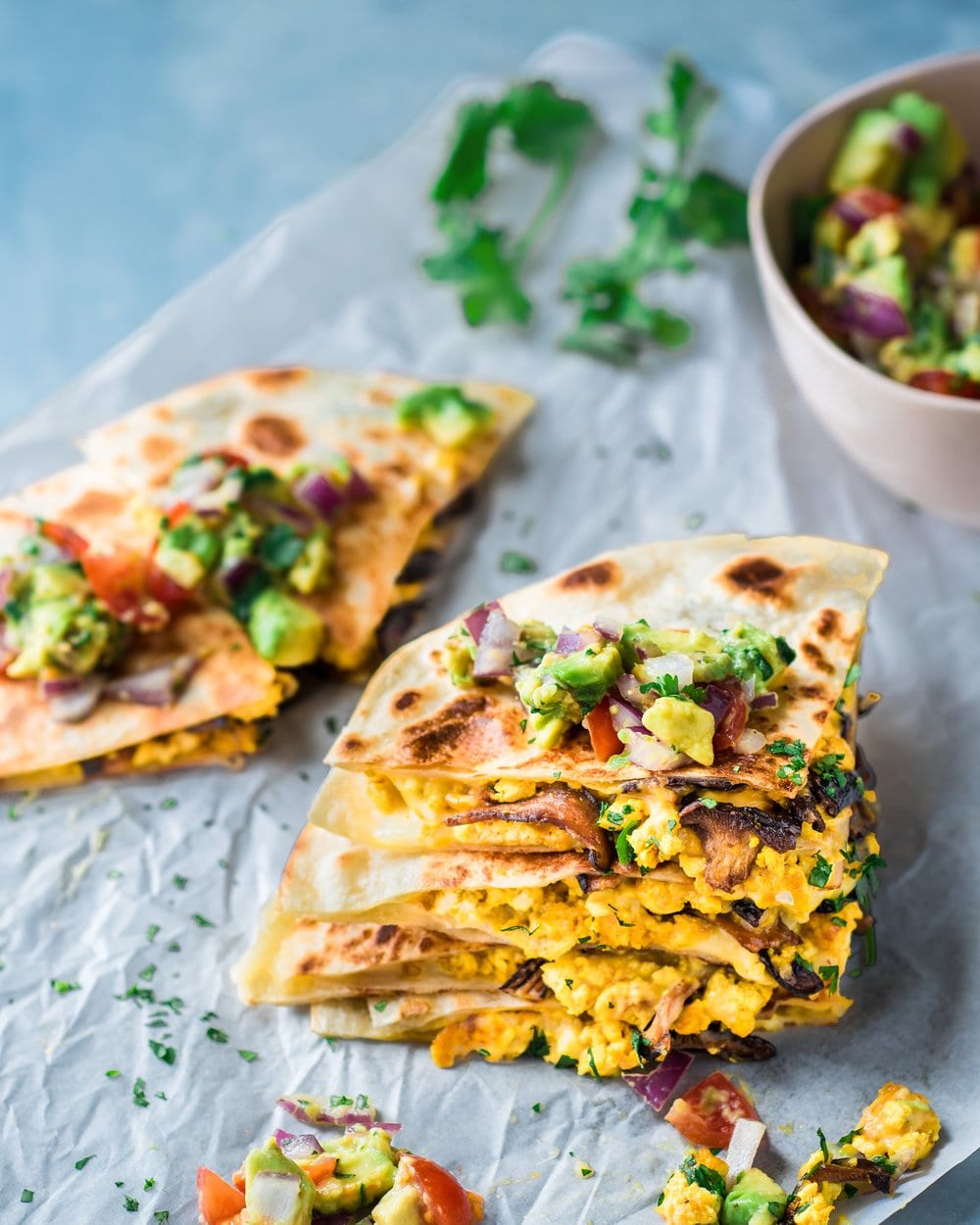 Quartered vegan quesadillas stacked on a piece of parchment paper.