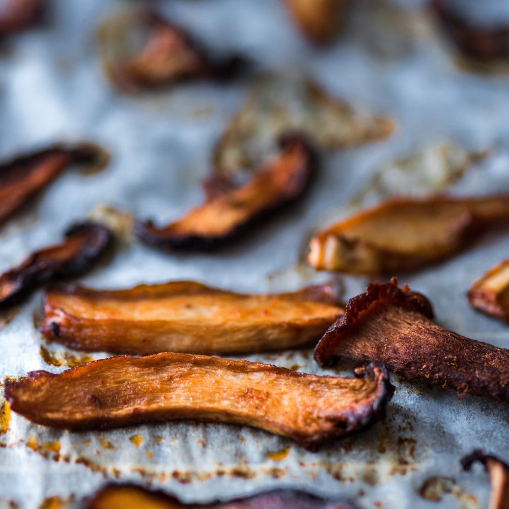 Close up of cooked mushroom bacon on a piece of parchment paper.