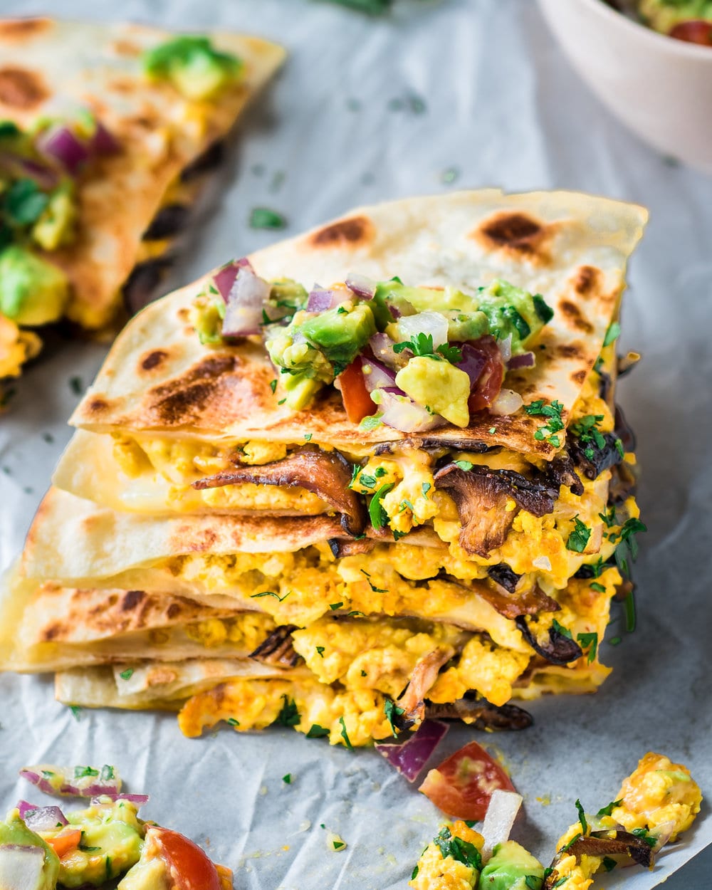 Salsa on top of a stack of four quartered quesadillas on a piece of parchment paper.