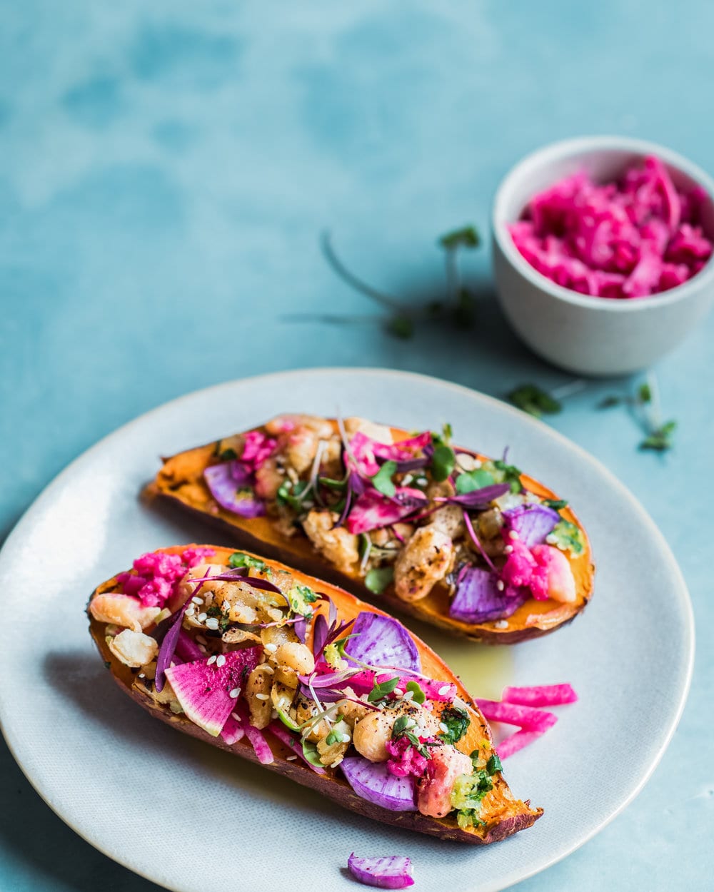 Two stuffed sweet potato halves on a plate on a blue table.