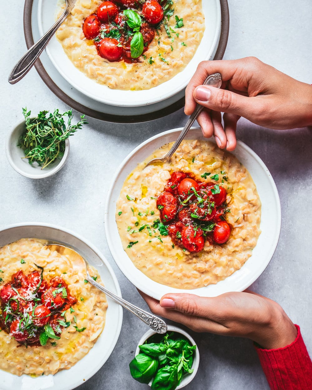 Woman holding bowl of Instant Pot Farro Risotto over a grey table.