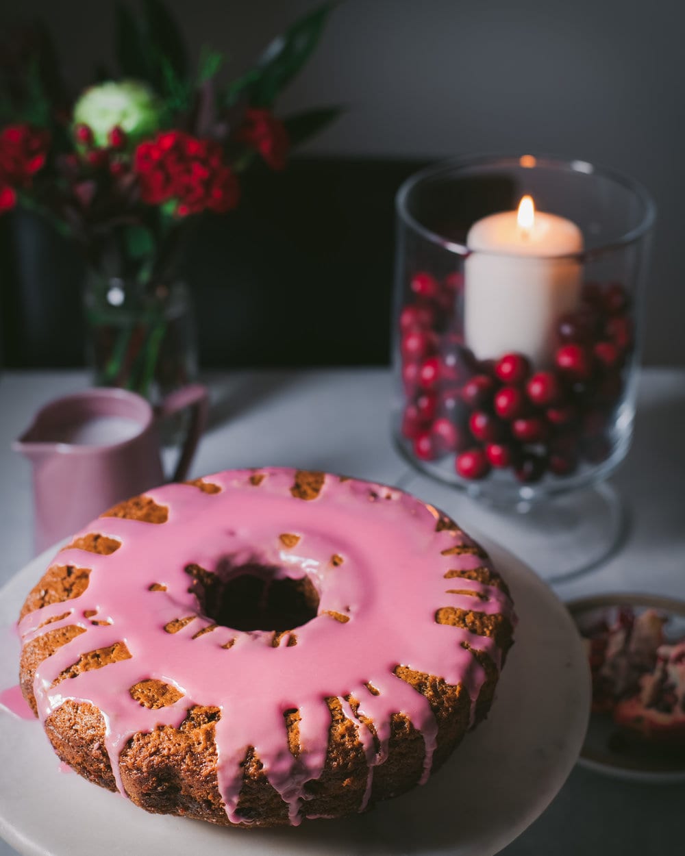 Bundt Cake with pomegranate glaze on a white cake stand.