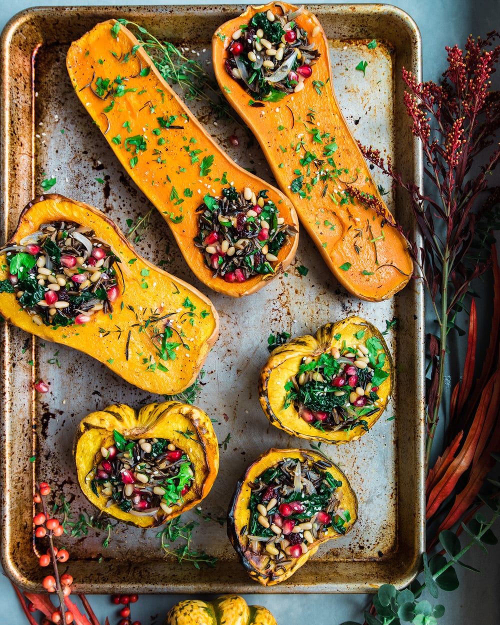 Six squash halves stuffed with wild rice mixture on a baking tray.