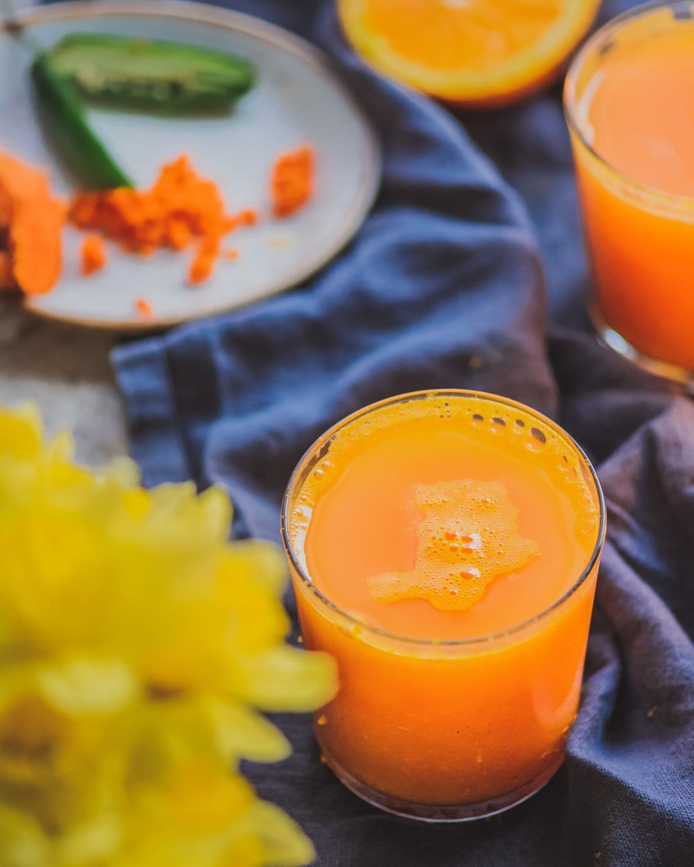 Glass of turmeric tonic on a blue cloth napkin on a table.