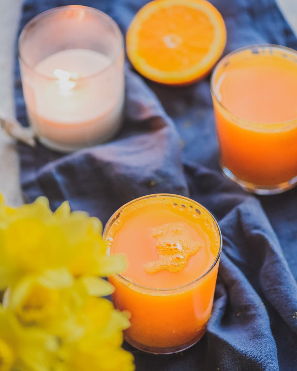 Two glasses of turmeric tonic on a blue cloth napkin on a table.