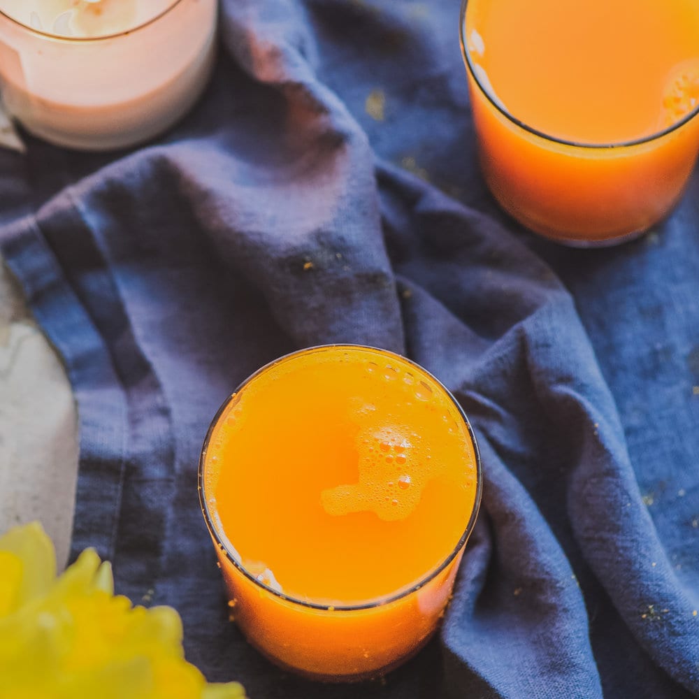 Two glasses of turmeric tonic on a blue cloth napkin on a table.