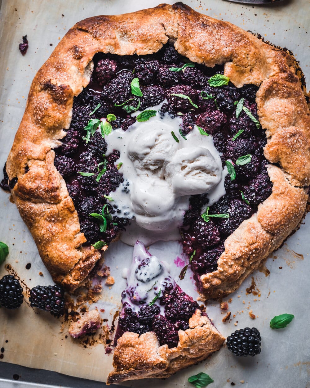 One slice cut from blackberry galette with herbs and ice cream.