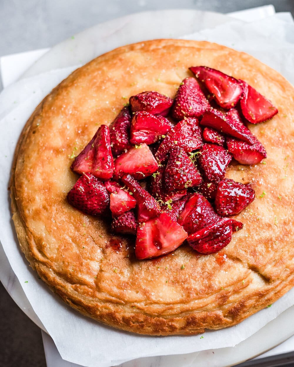 Vegan Dutch Baby with Roasted Strawberries on marble serving board.