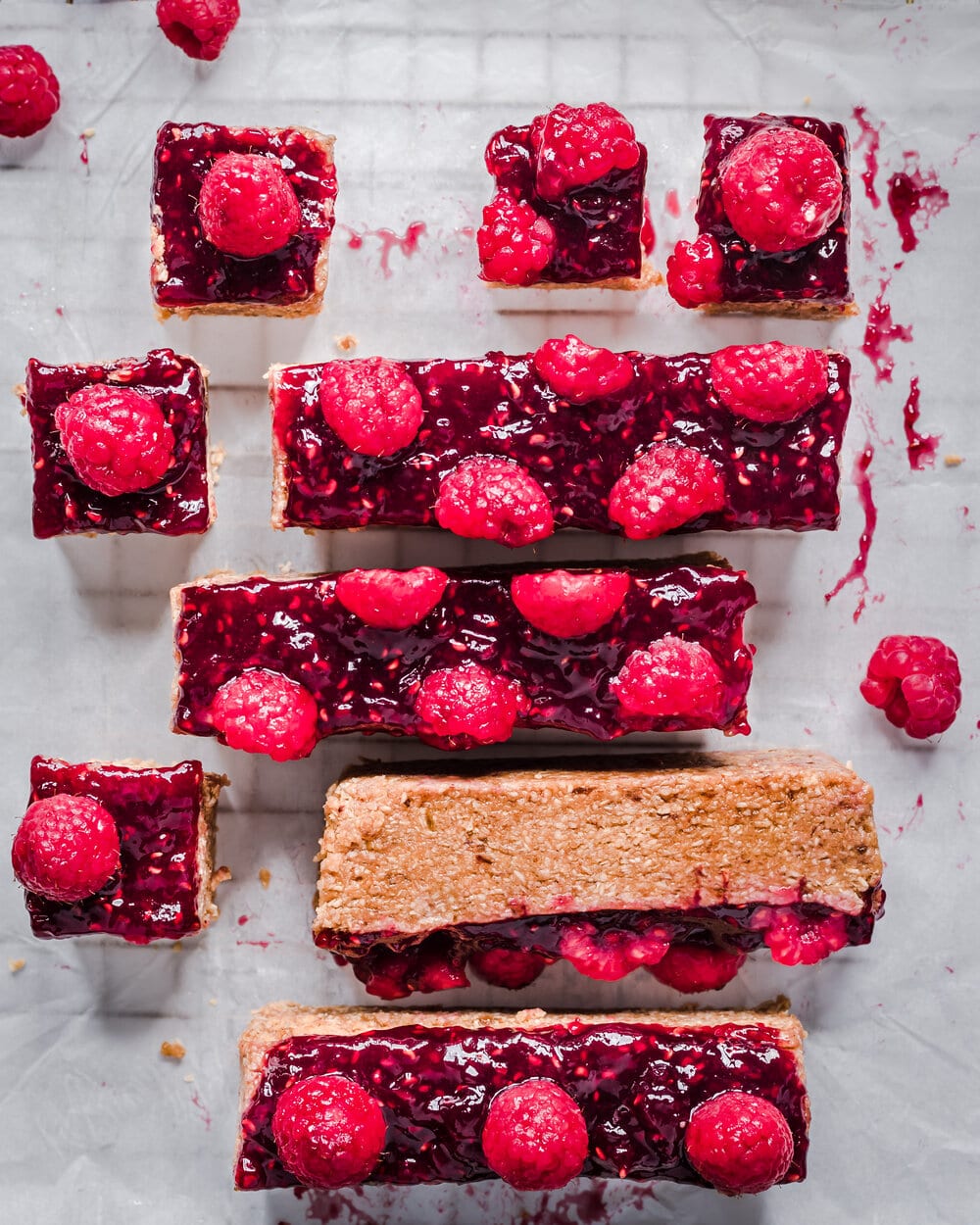 Overhead view of small pb&j bites and large bars on parchment paper on a cooling rack.