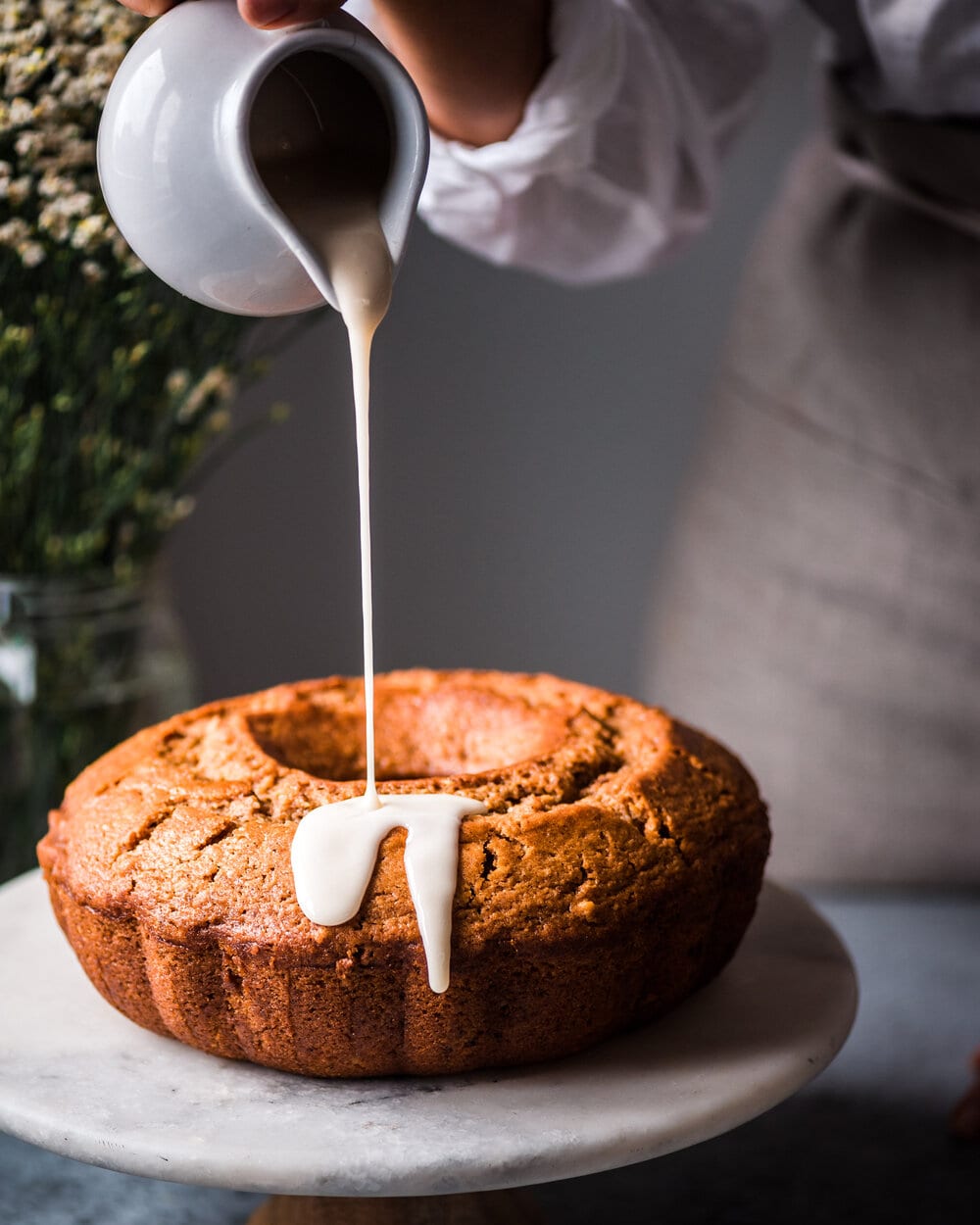 Vegan Apple Cinnamon Bundt Cake. pouring icing on vegan bundt cake.