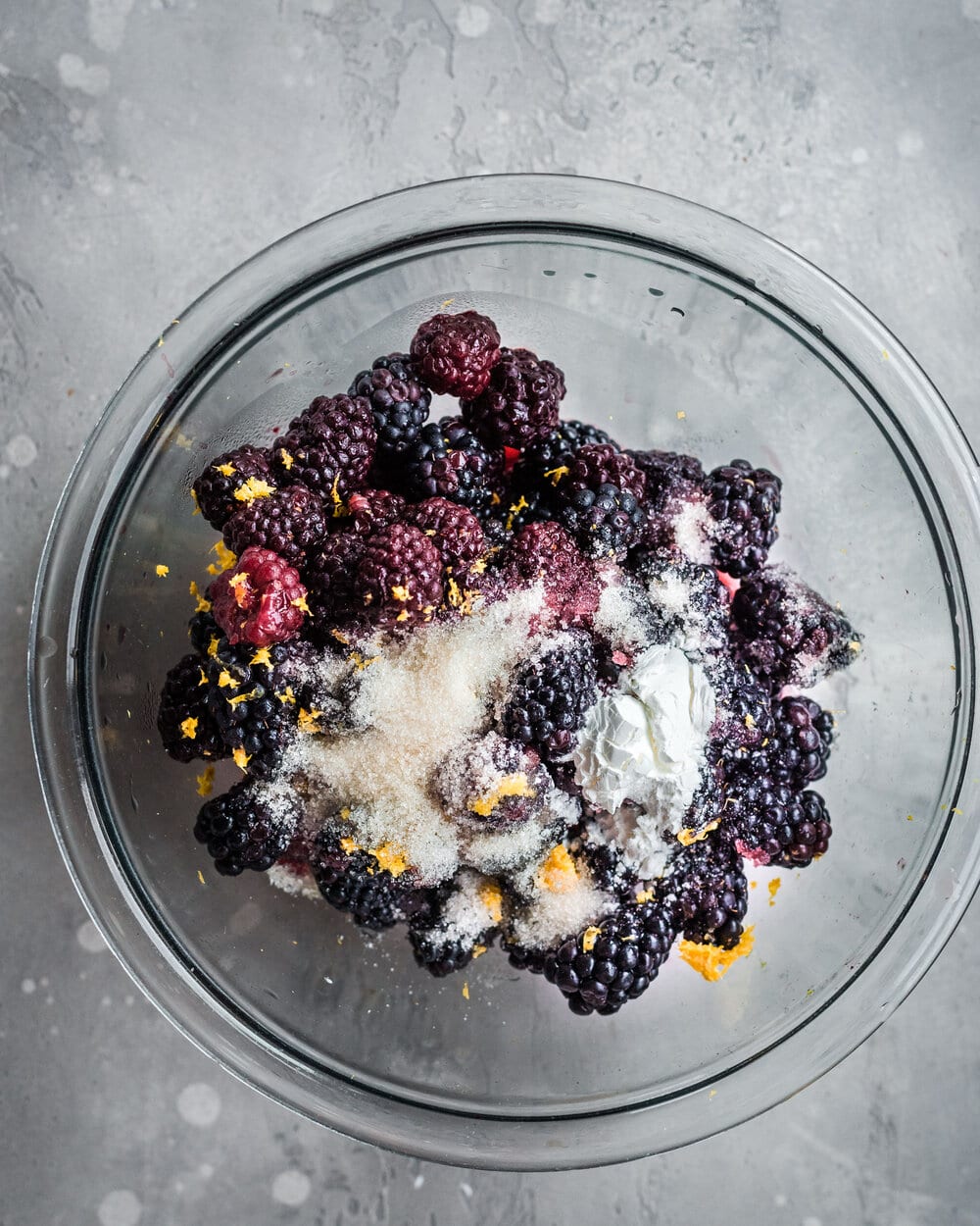 Blackberries, sugar and zest in a glass bowl.