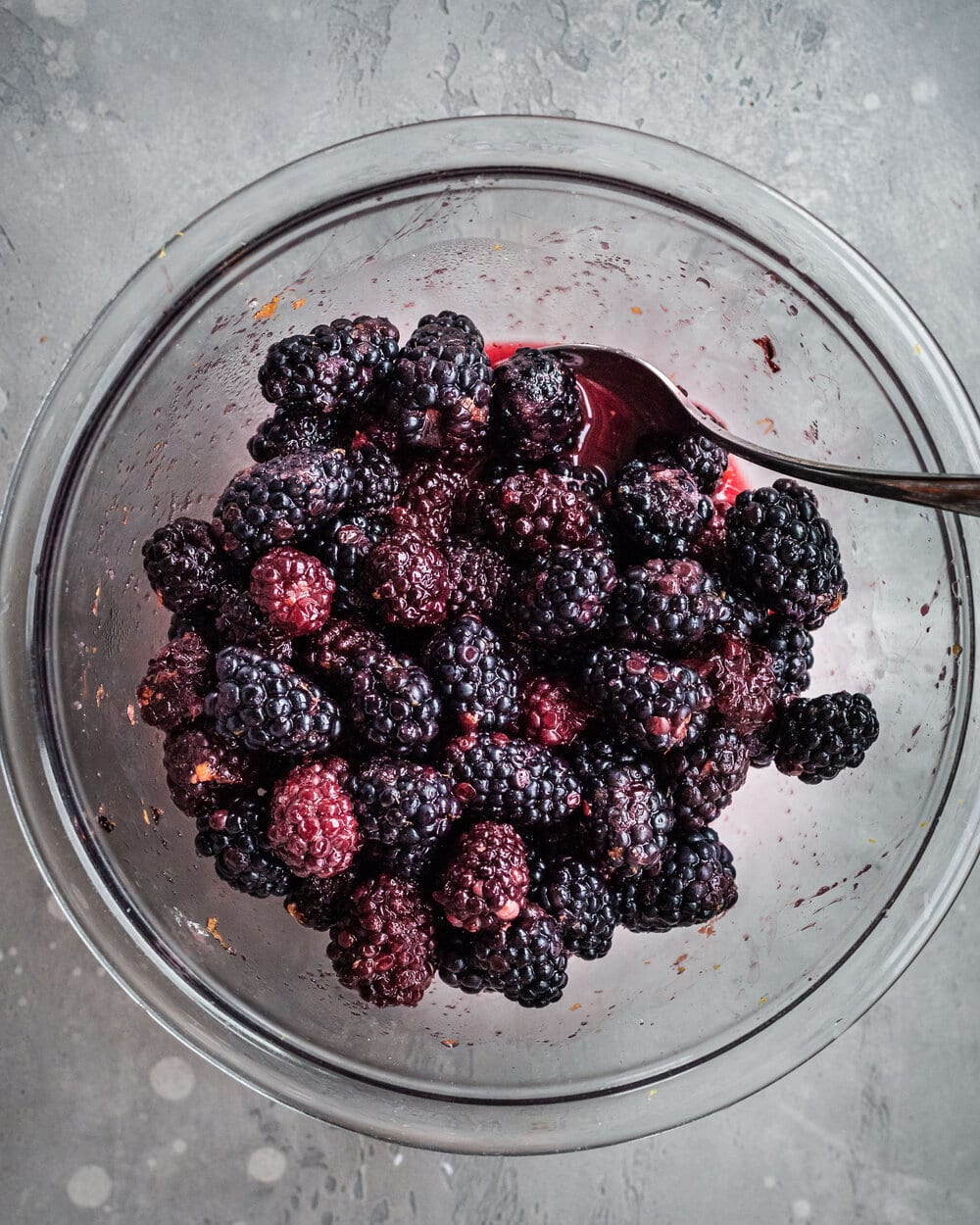 Mixed blackberries, sugar and zest in a glass bowl.