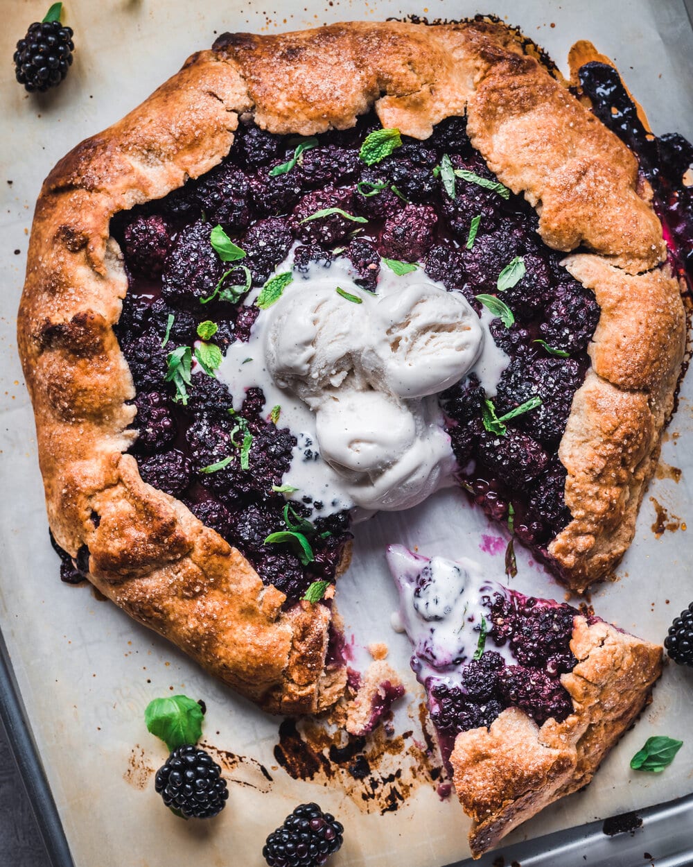 One slice cut from cooked blackberry galette with mint, basil and ice cream.