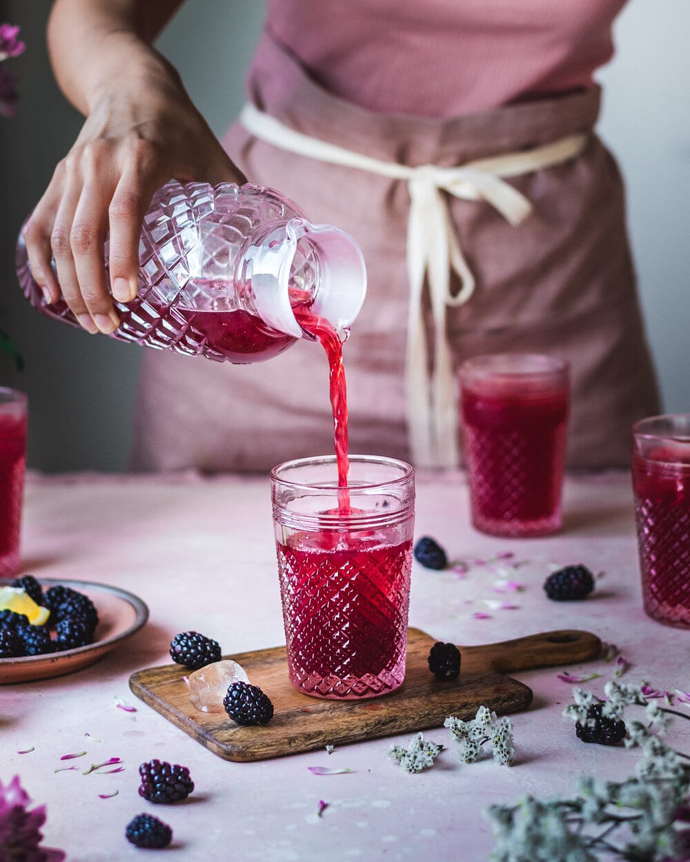 woman pouring blackberry lemonade into cup.