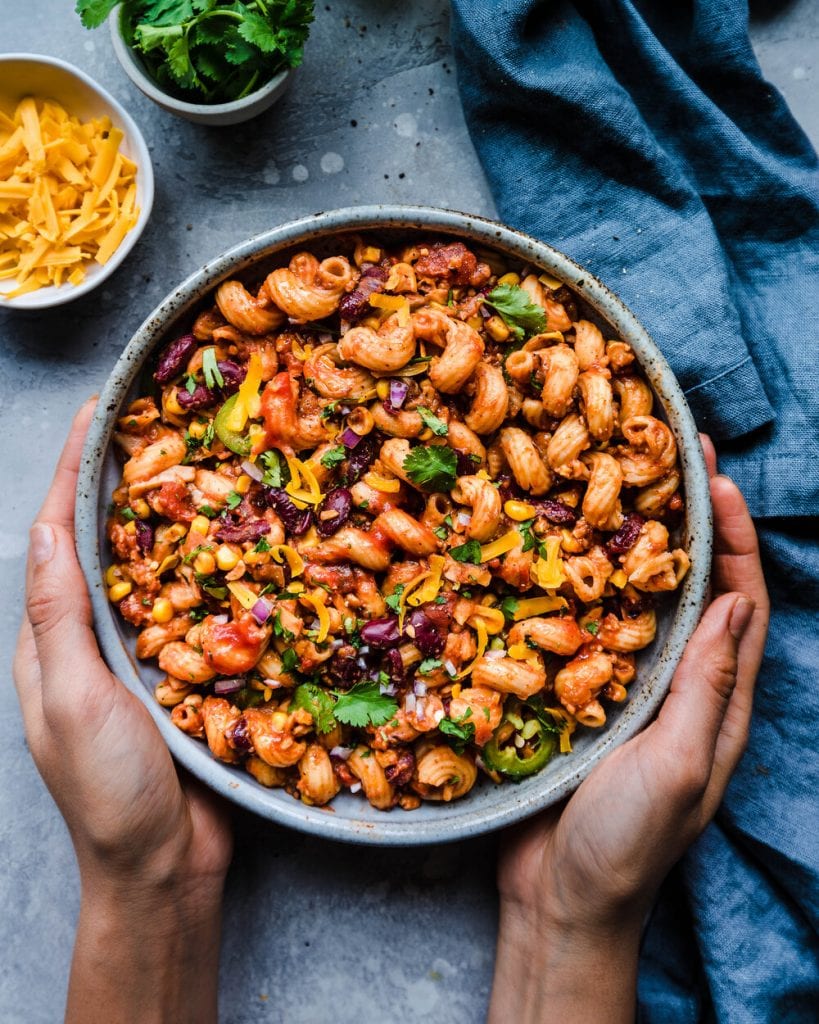 woman's hands holding bowl of vegan mac and cheese