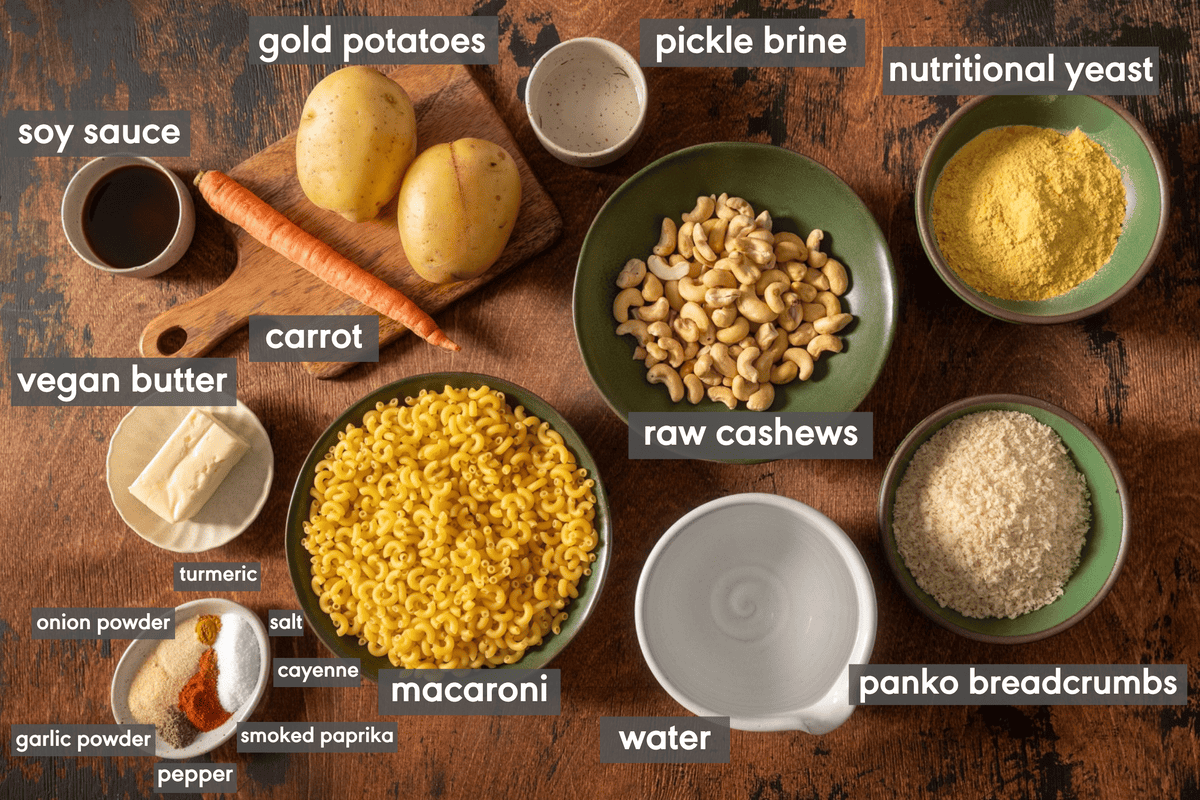 Ingredients in bowls for vegan mac and cheese laid out on a wooden table.