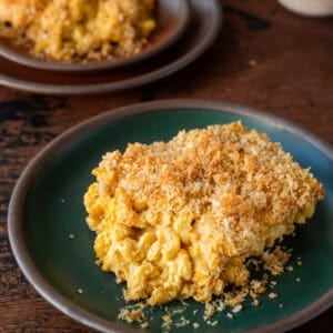 a gooey slice of vegan mac and cheese with crispy topping on a green plate.