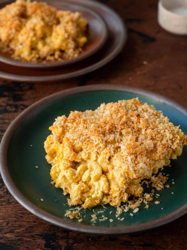 a gooey slice of vegan mac and cheese with crispy topping on a green plate.
