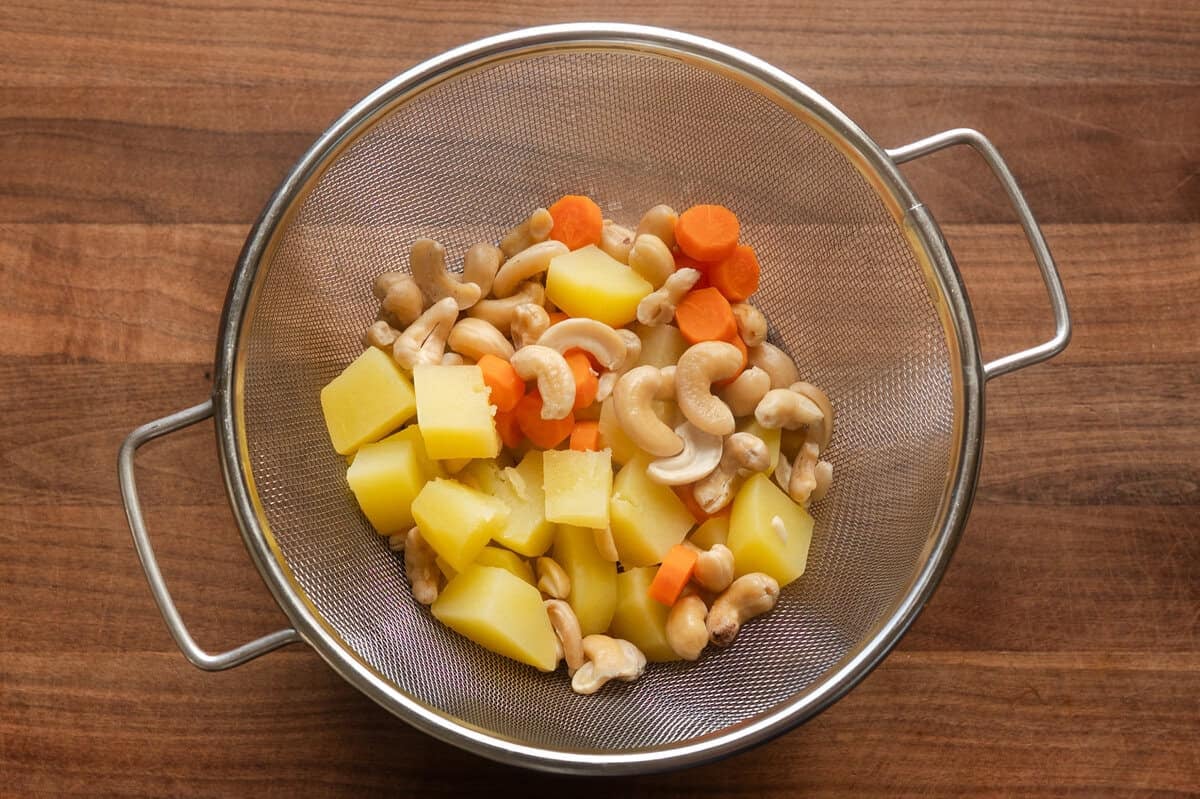 cooked carrots, potatoes, and cashews in a colander.