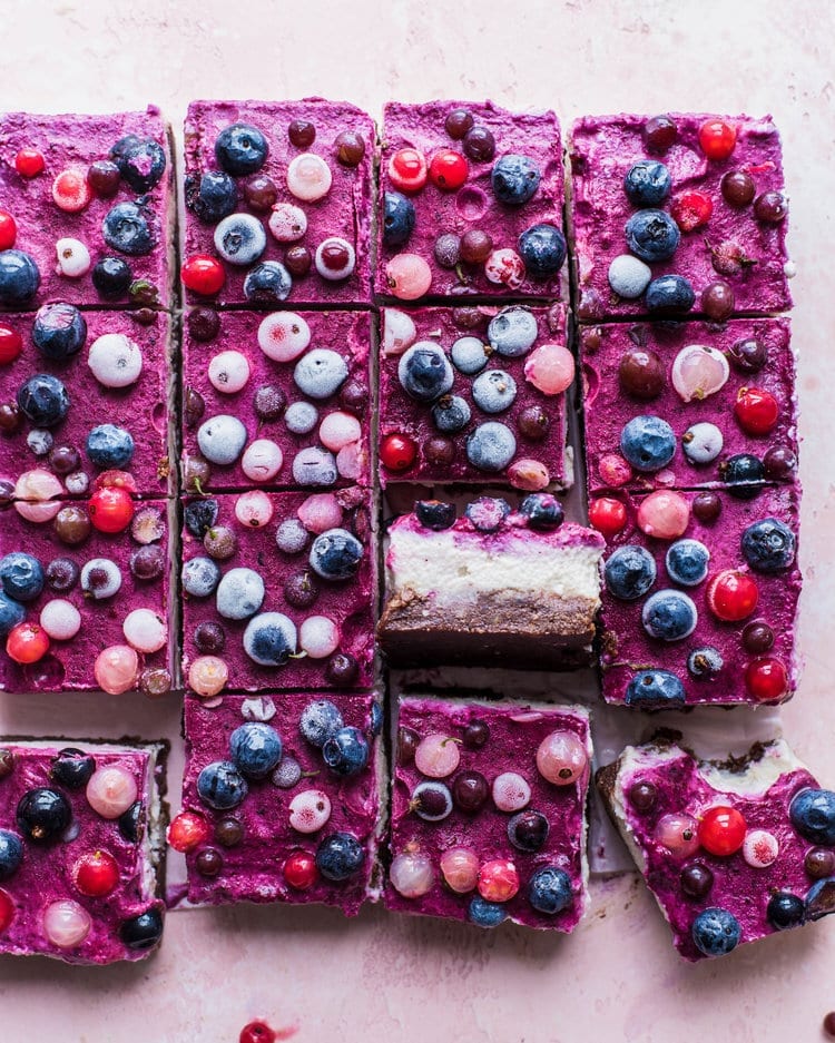 berry cheesecake bars on a pink table.