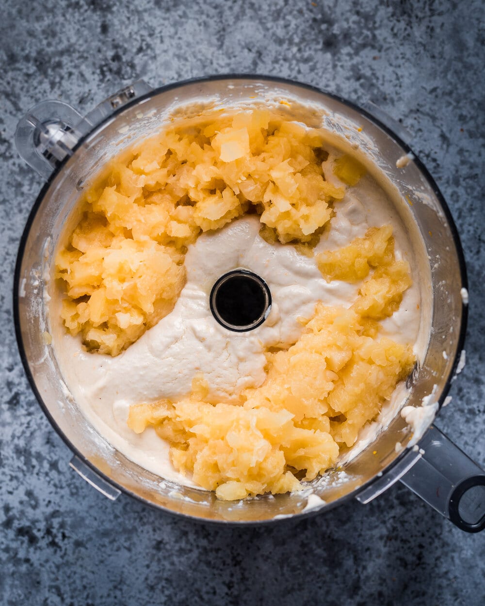 crushed pineapple being added to batter in food processor