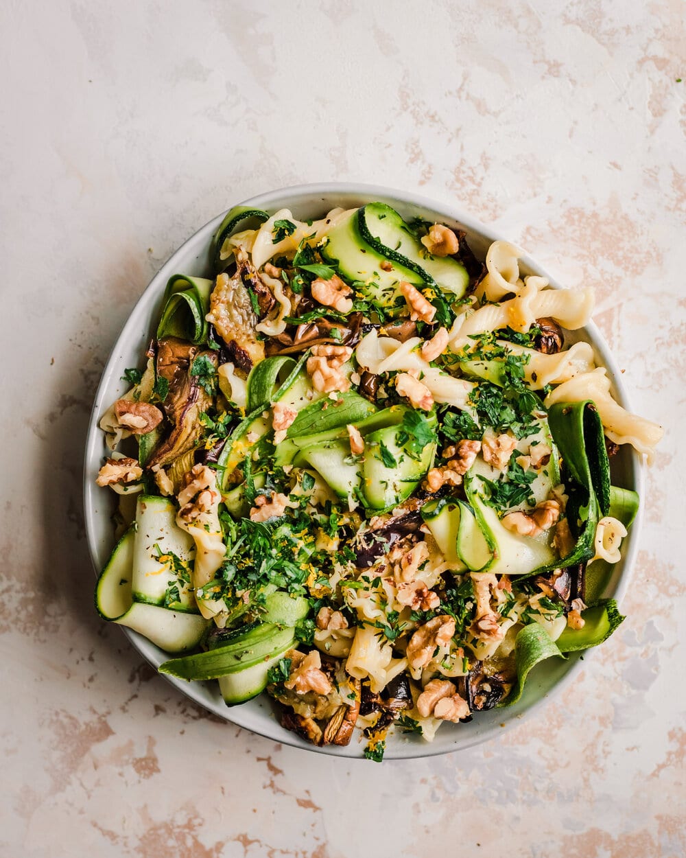 vegan roasted eggplant pasta with zucchini ribbons and walnuts in a white bowl. 