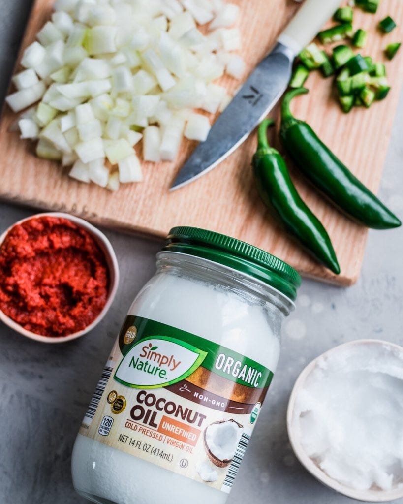 Coconut oil resting on cutting board with other ingredients for West African Peanut Stew.