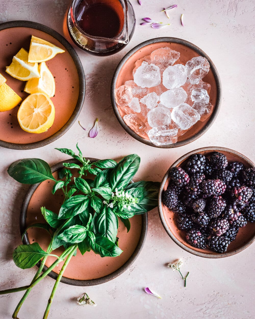 a variety of plates containing lemons, blackerry, basil and ice.