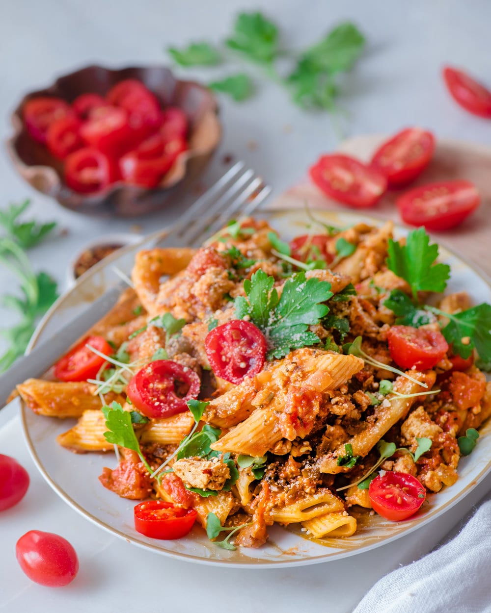 Bolognese penne in a white bowl on white table.