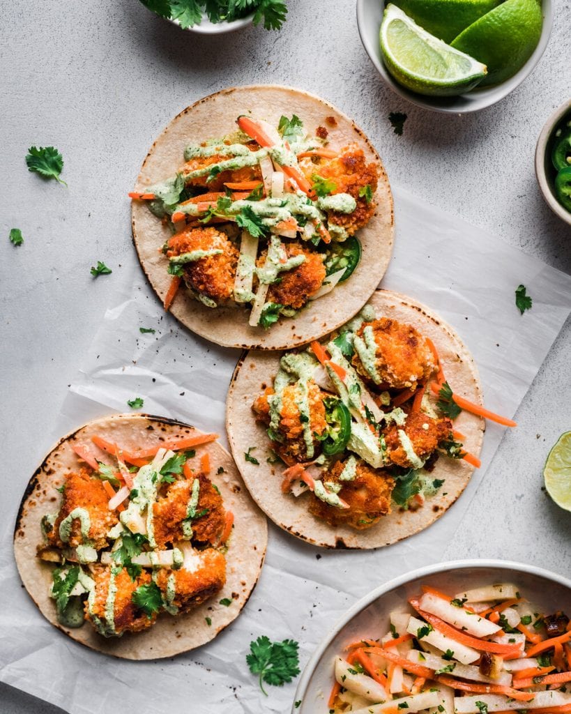 three tacos with baked crispy cauliflower on parchment paper