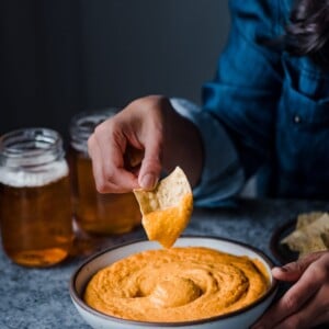 dipping tortilla chips into Cheesy Buffalo Cauliflower Dip