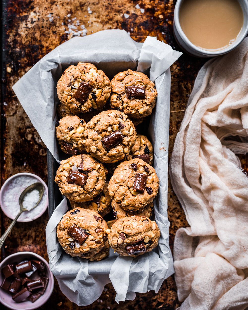 Loaf tin lined with parchment paper filled with chocolate chunk cookies on top of a baking sheet.