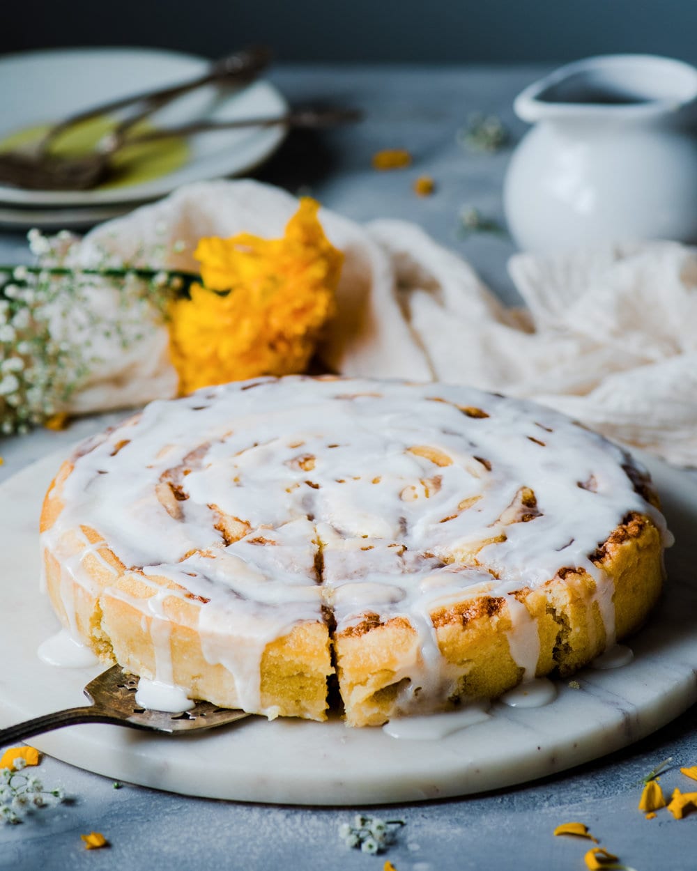 Sliced cinnamon roll cake on a round marble serving platter.