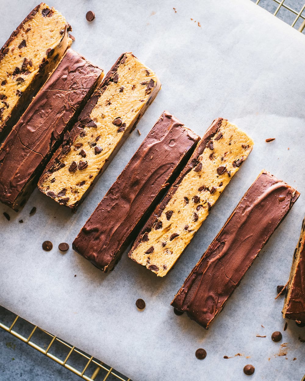chocolate chip cookie dough bars arranged in a line on parchment paper.