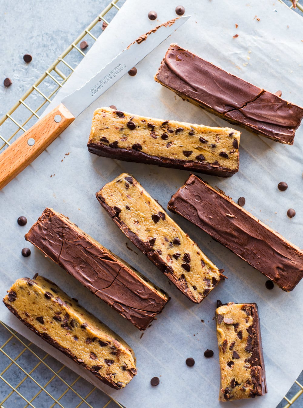 cookie dough bars covered in chocolate on wire rack with knife