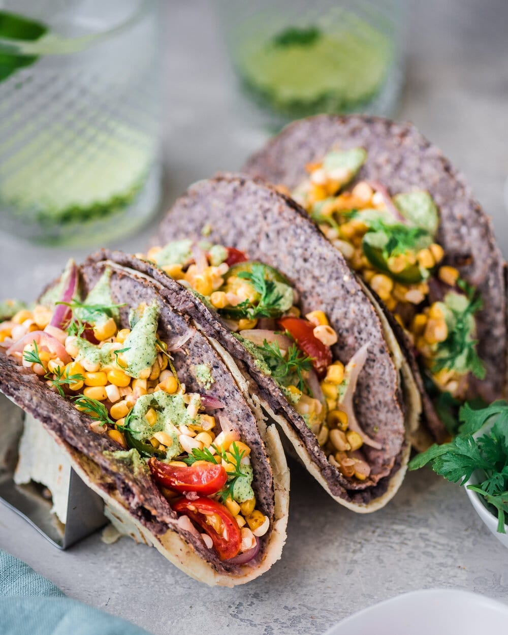 Three black bean and corn salad tacos in a taco holder on a table.