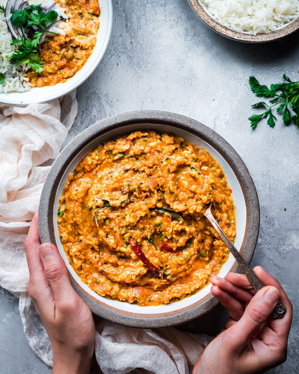 woman's hands holding bowl of dal tadka