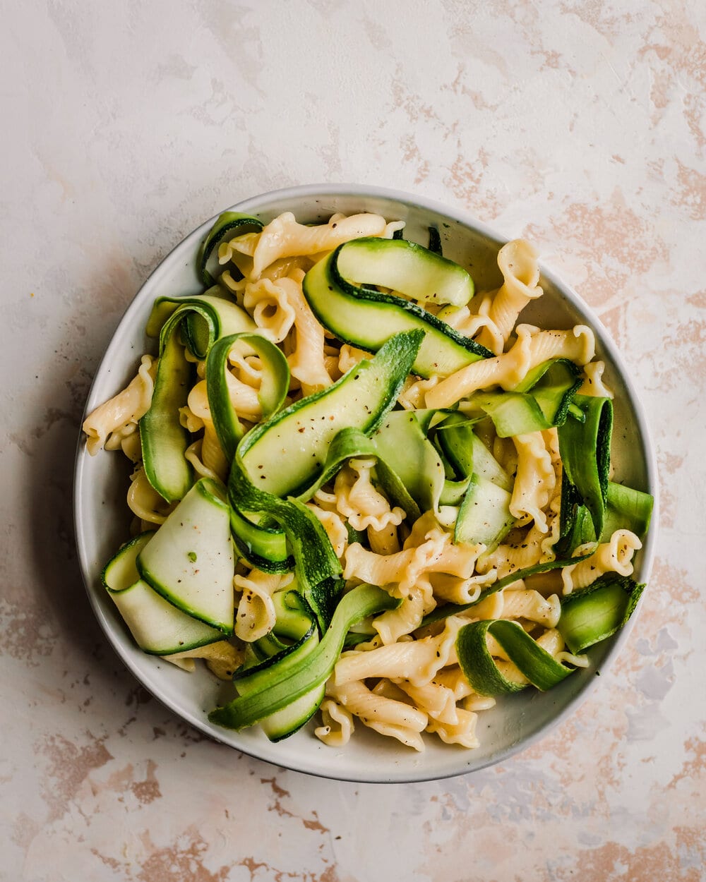 pasta paired with zucchini ribbons in a ceramic bowl. 