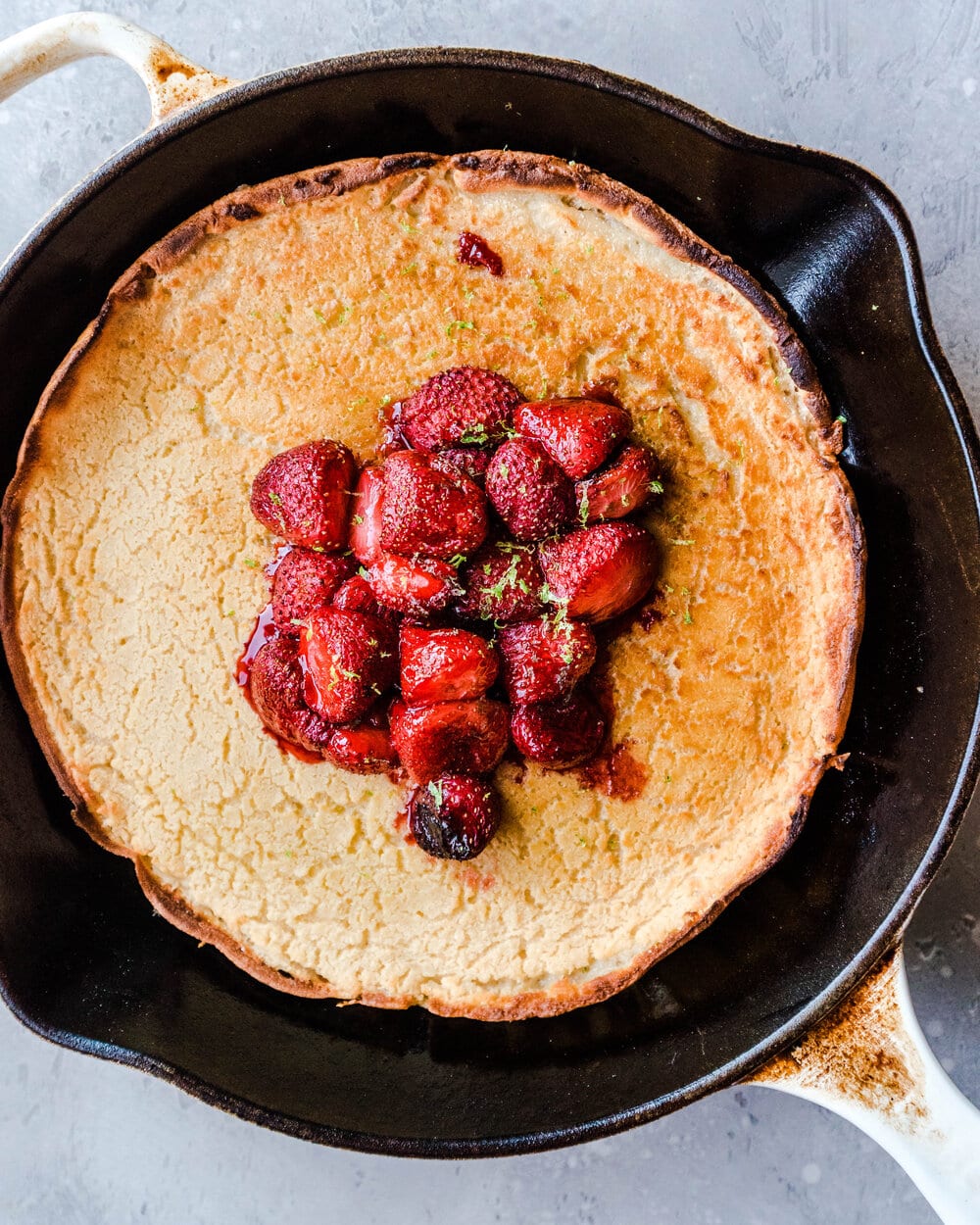 Dutch baby with roasted strawberries in skillet.