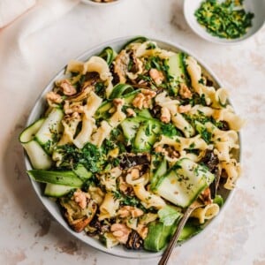 bowl of roasted eggplant pasta with fork and ingredient bowls to the side of it