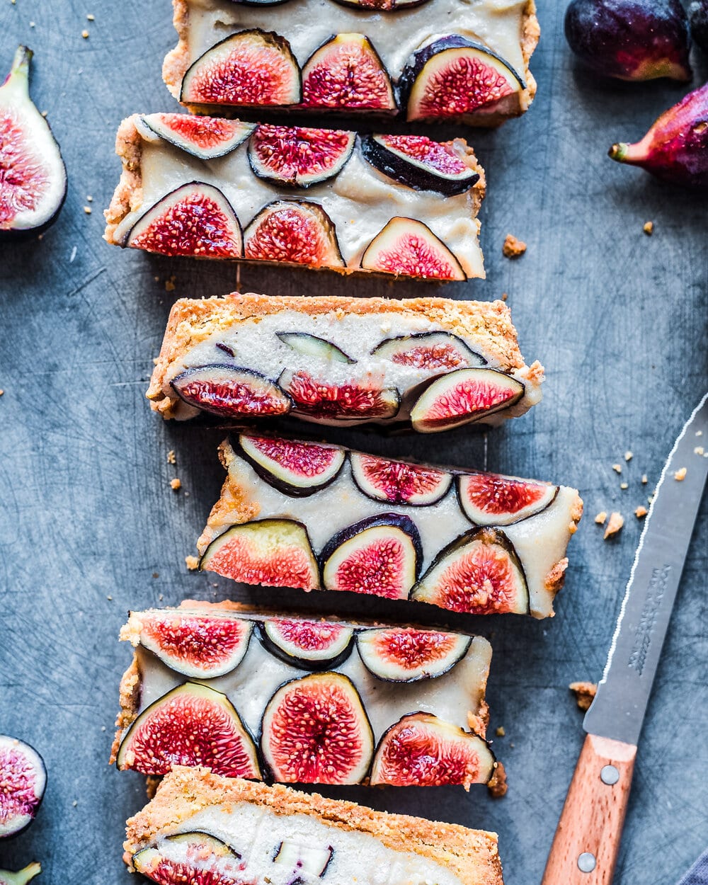 Slices of fig tart next to knife and figs on table.