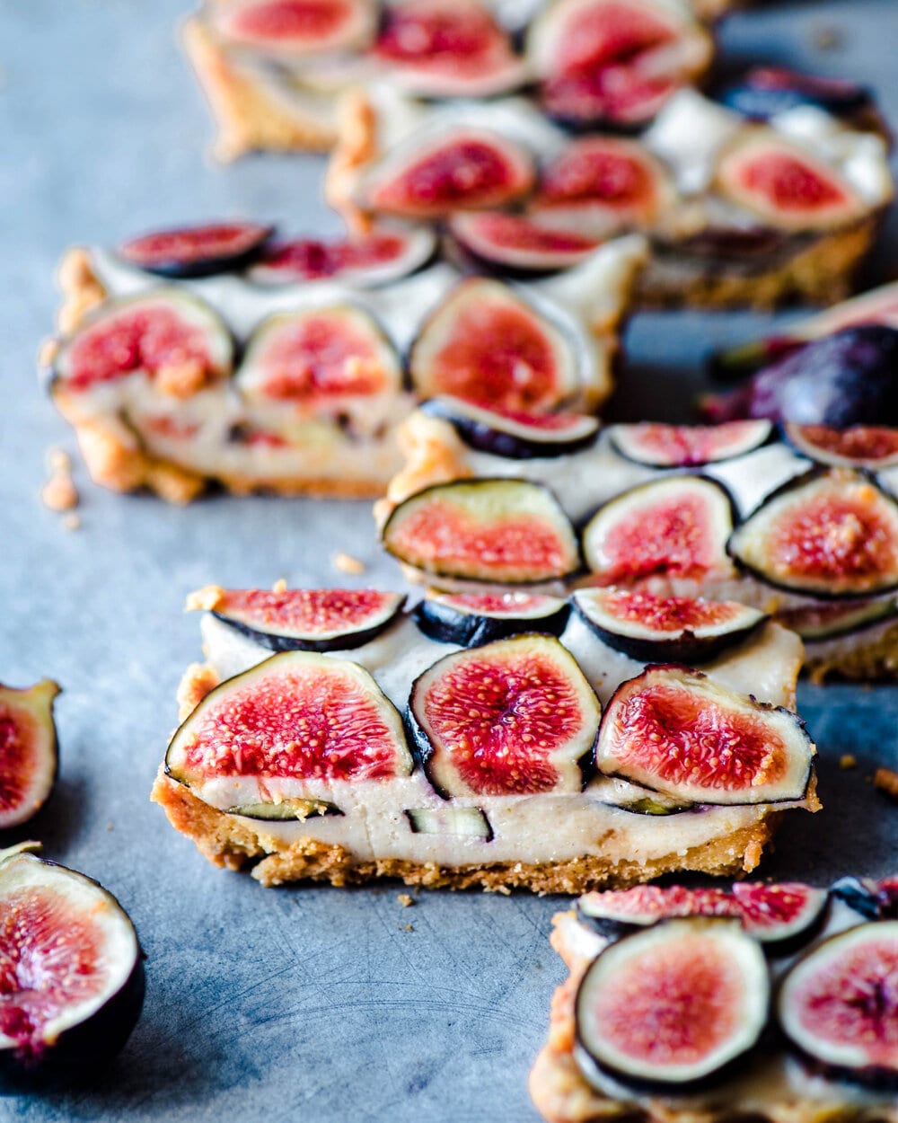 Side close up view of slices of fig tart on blue-grey table.