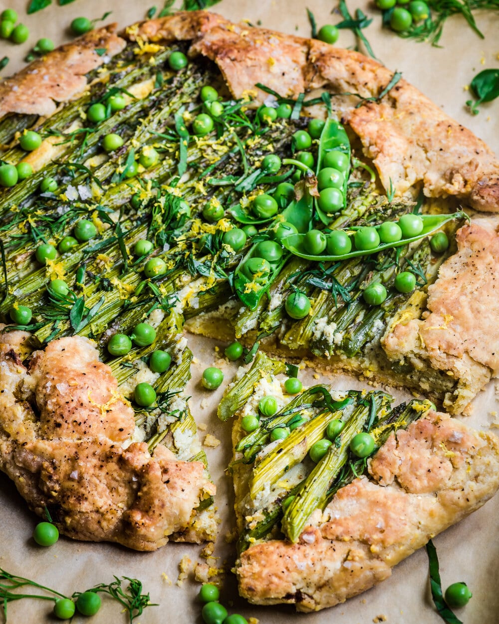 Baked galette with fresh peas with one slice cut from it.