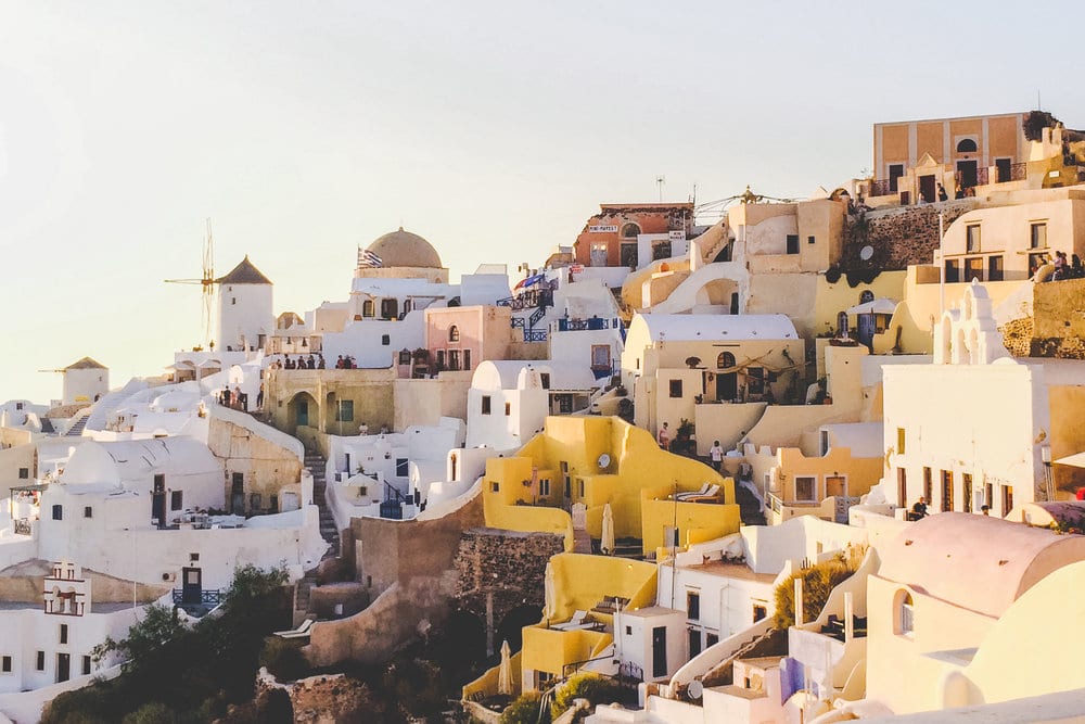 Hillside in Greece with various white, tan and yellow houses.