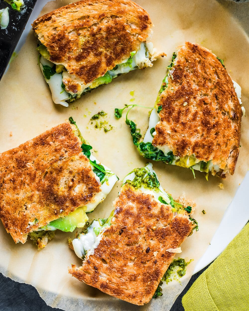 Grilled cheese cut into quarters on a piece of parchment paper.