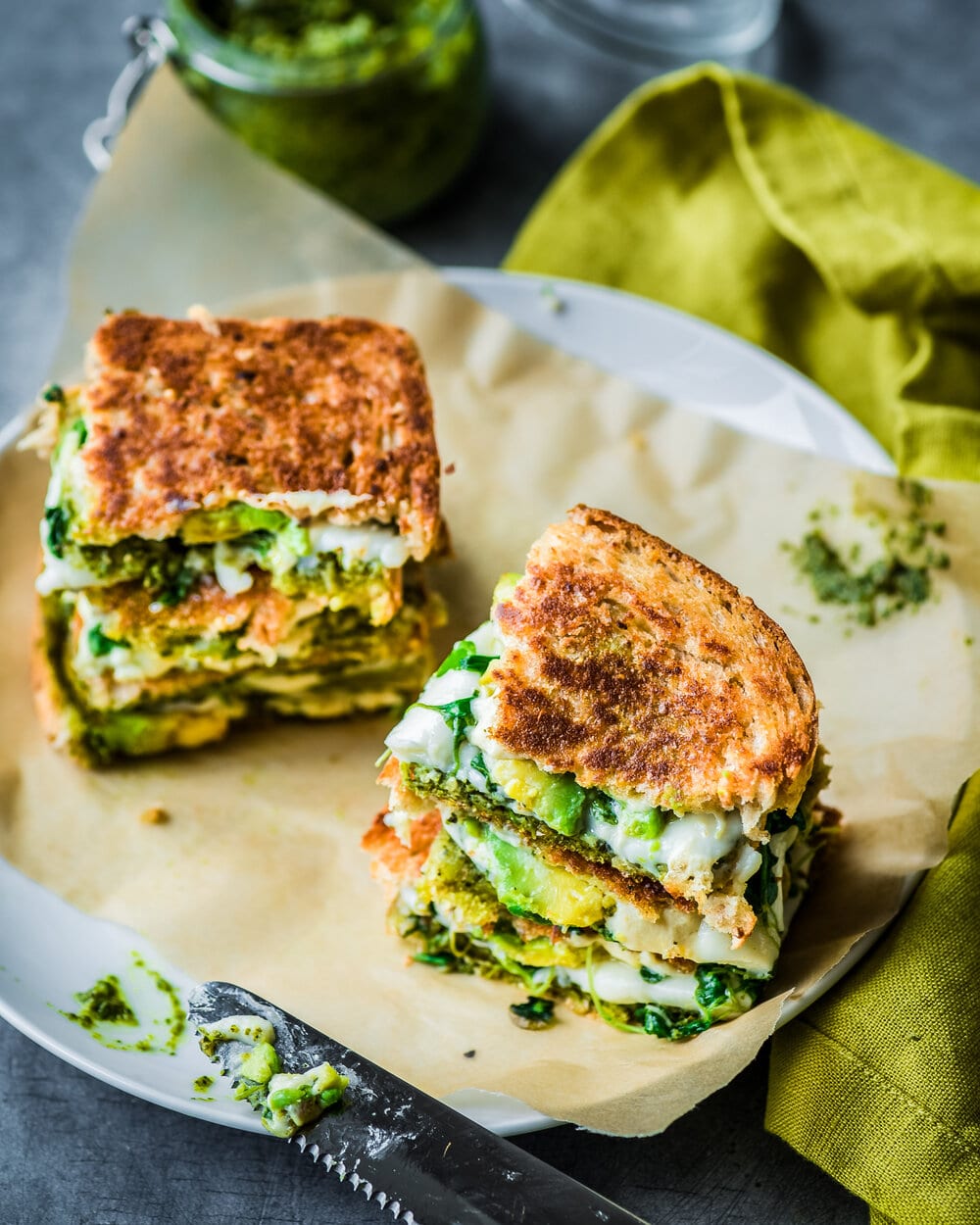 Two stacks of quartered grilled cheeses on a piece of parchment paper.