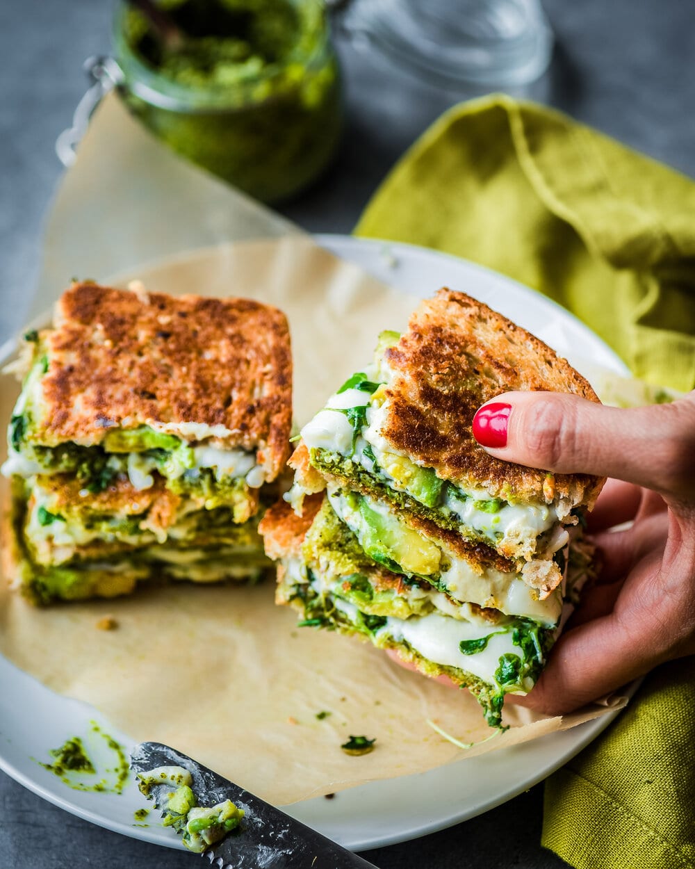 Woman holding up two stacked quartered grilled cheeses.