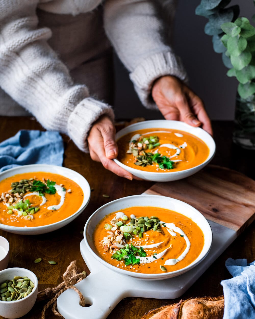 Person placing bowl of soup on a table.